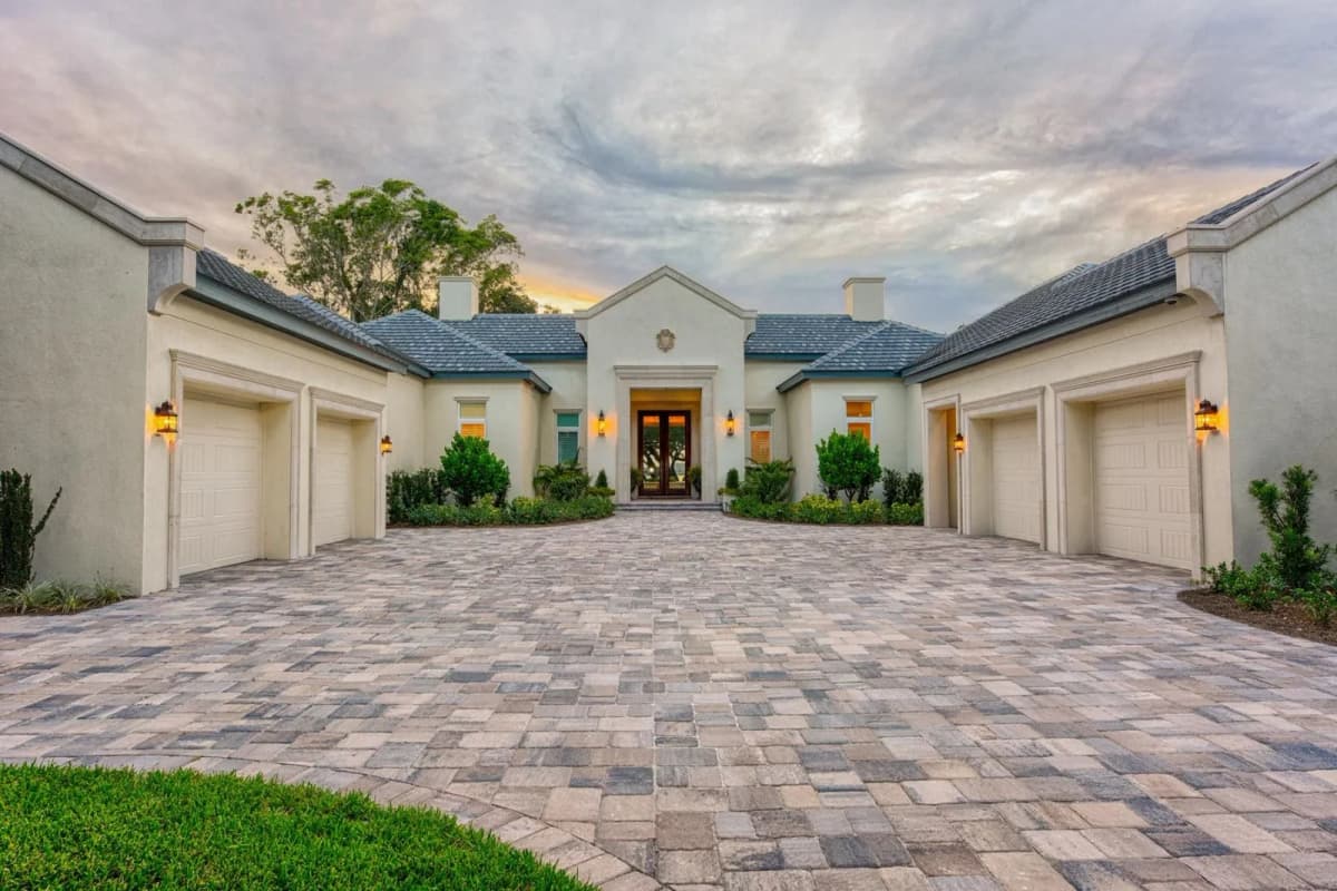 French Provincial custom home with paver motor court at sunset