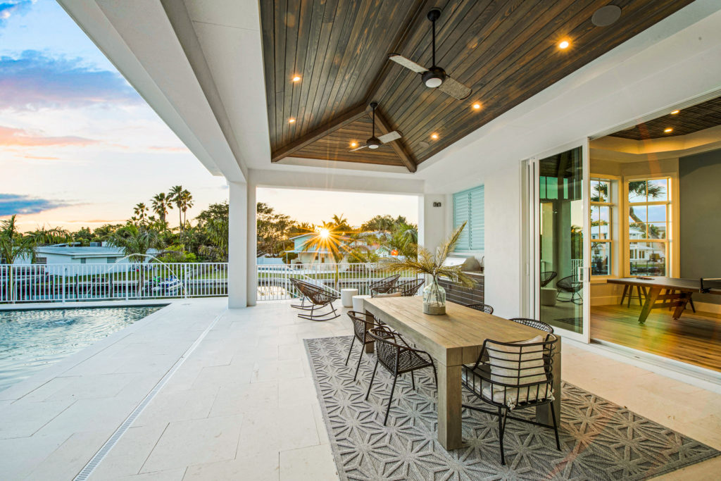 Covered outdoor living area with pool and sunset views at a luxury custom home in Sarasota FL built by Nutter Custom Construction
