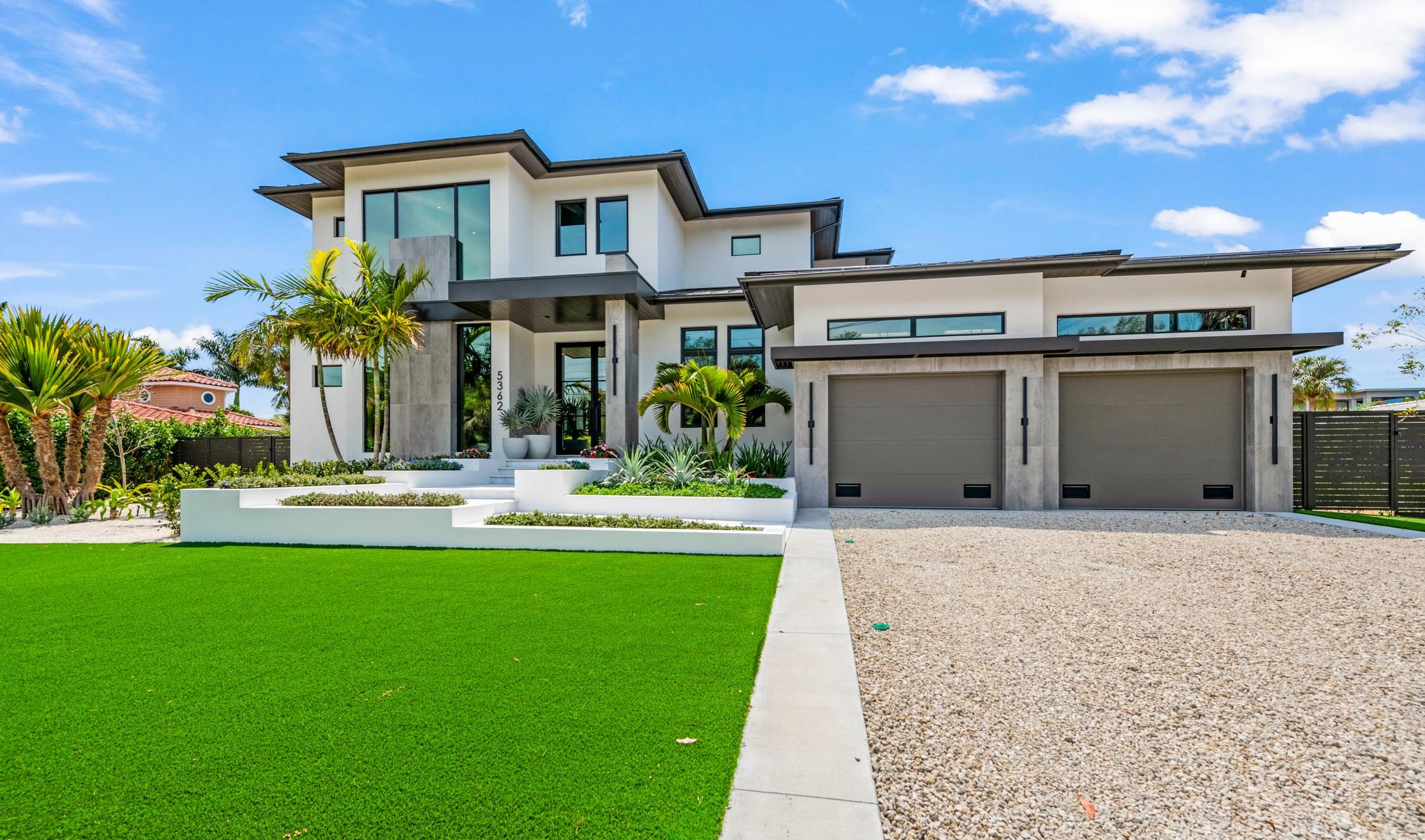 Modern two story luxury custom home exterior with two car garage and tropical landscaping in Sarasota FL built by Nutter Custom Construction