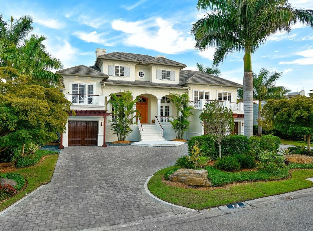 British West Indies style luxury custom home with paver driveway and tropical landscaping on Siesta Key FL built by Nutter Custom Construction
