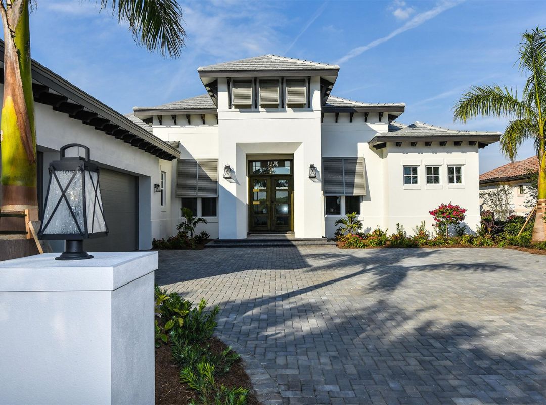 Coastal Zen luxury custom home with paver driveway and tropical landscaping built by Nutter Custom Construction on Siesta Key FL