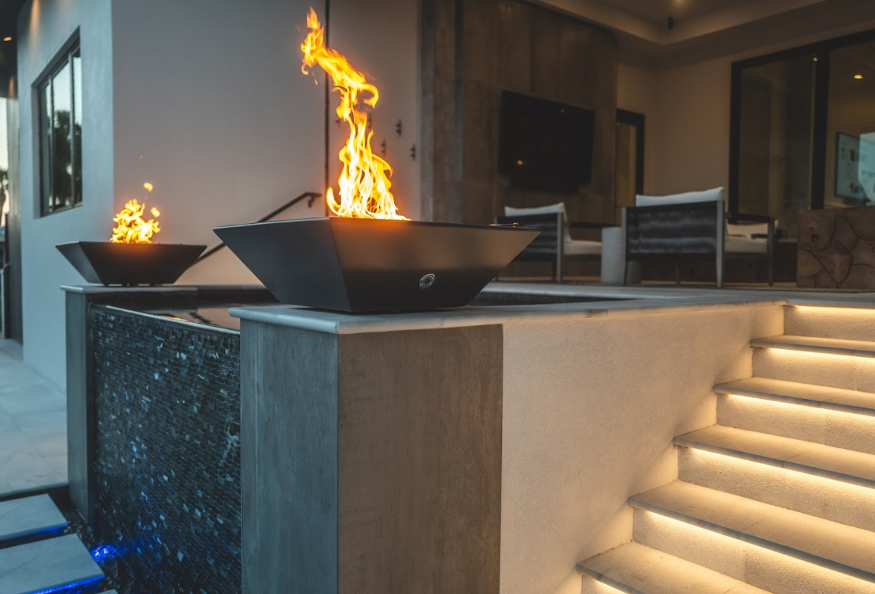 Luxury custom home outdoor fire bowl feature with illuminated steps and seating area at night in Sarasota FL by Nutter Custom Construction